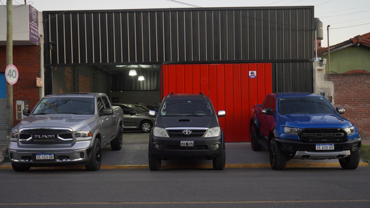 Frente del local de Punto Bella Vista con tres camionetas estacionadas
